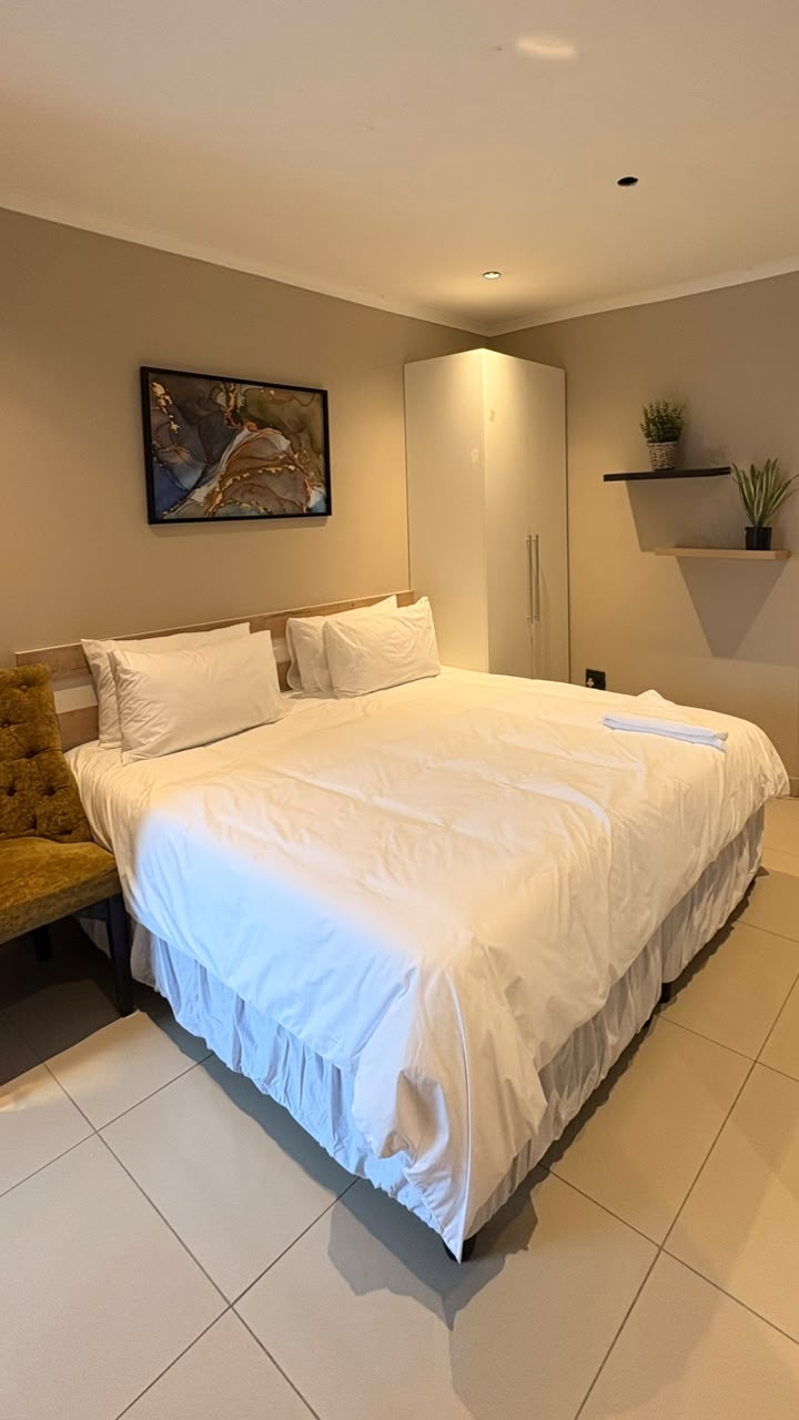 Warmly lit Sponono luxury suite with crisp white bedding and a velvet accent chair